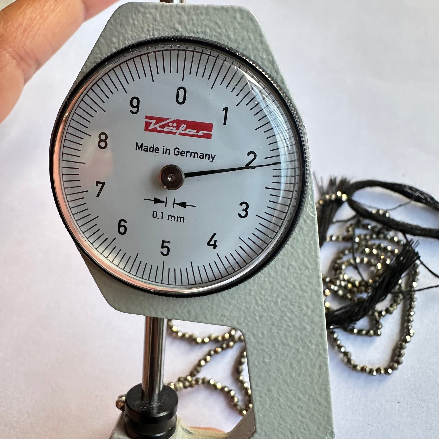 A dial gauge measures the Pyrite faceted rondelle 2.1mm gemstone, ensuring precise sizing.