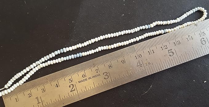 A ruler placed beside a strand of white faceted rondelle beads, highlighting the Strand length on a table surface