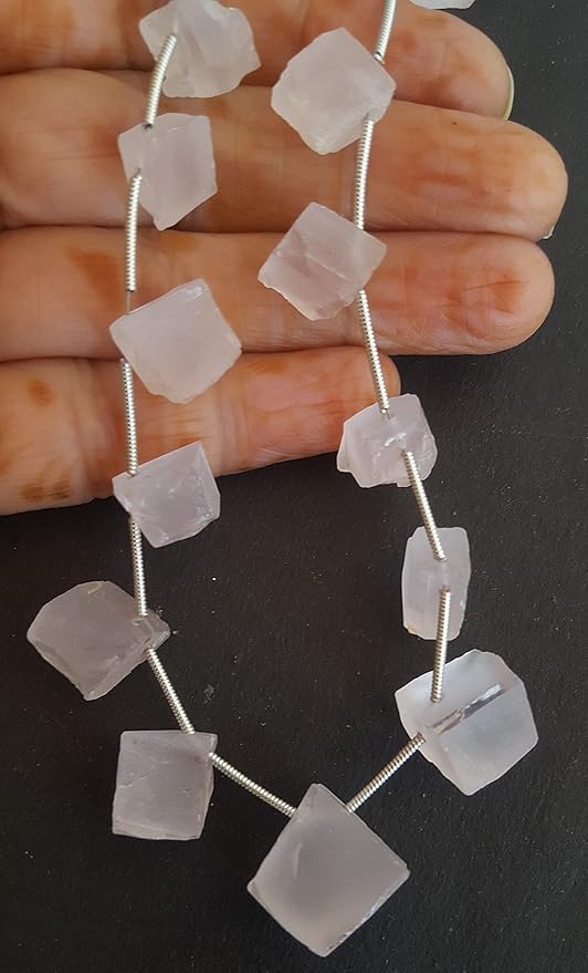 A person holding a rose quartz rough gemstone strand, showcasing its facets and elegant design.