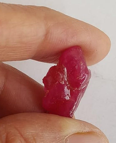 A person holds a vibrant ruby rough beads emphasising its size.