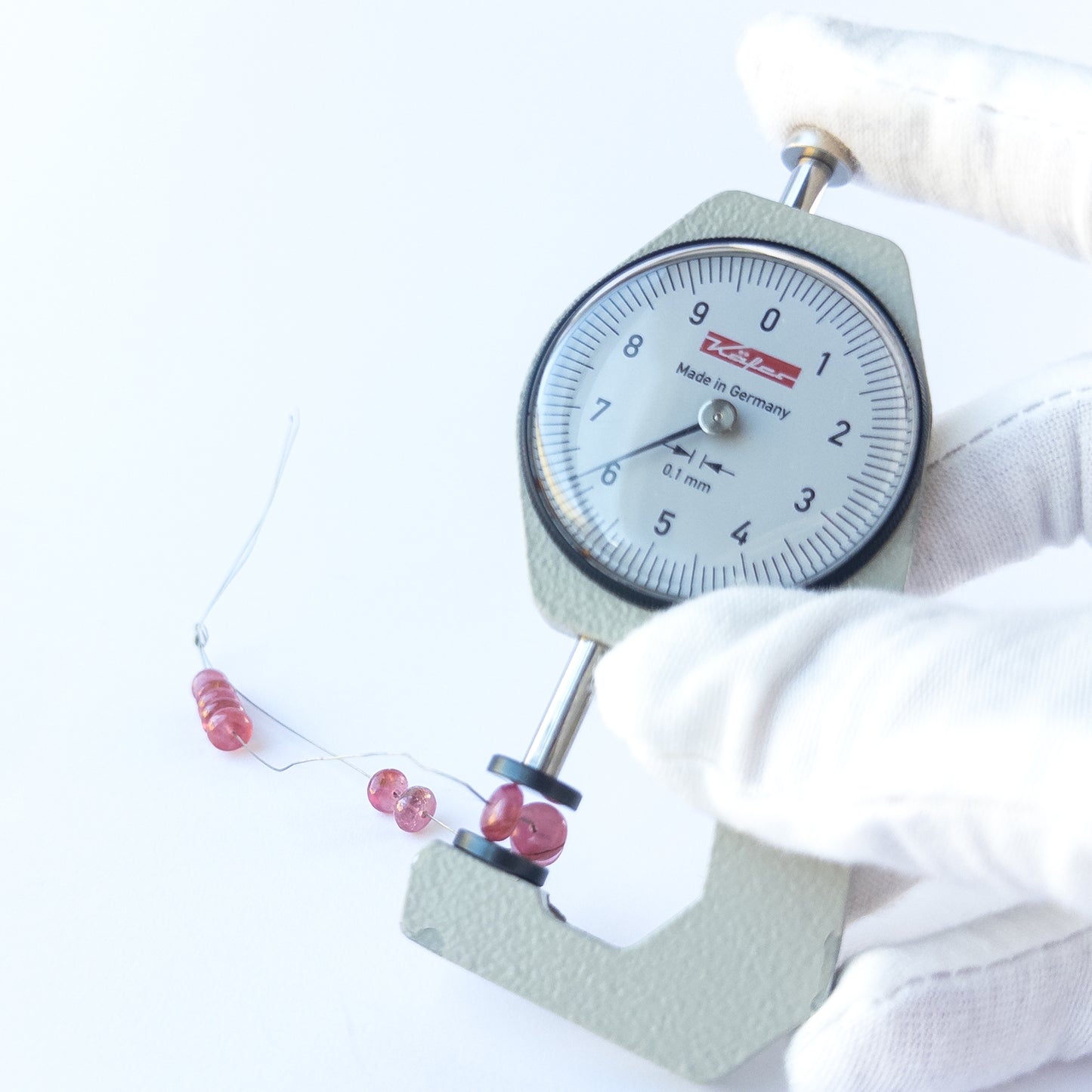 A dial gauge measures the Ruby smooth rondelle 5–6mm gemstone.