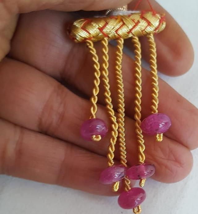 A person holding a ruby smooth rondelle gemstone strand, showcasing its pink facets and elegant design.