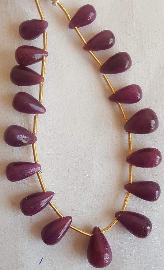 A stunning red ruby tear drop gemstones, elegantly hung from a delicate gold string.