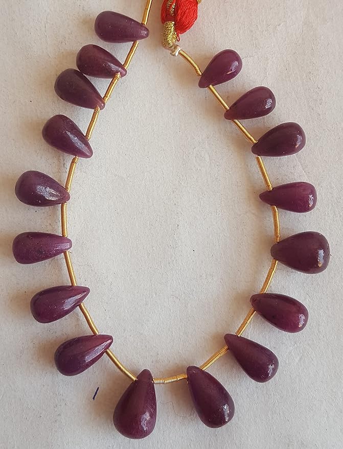 A vibrant ruby stone, attached to a luxurious gold tassel, showcasing its beauty and elegance.