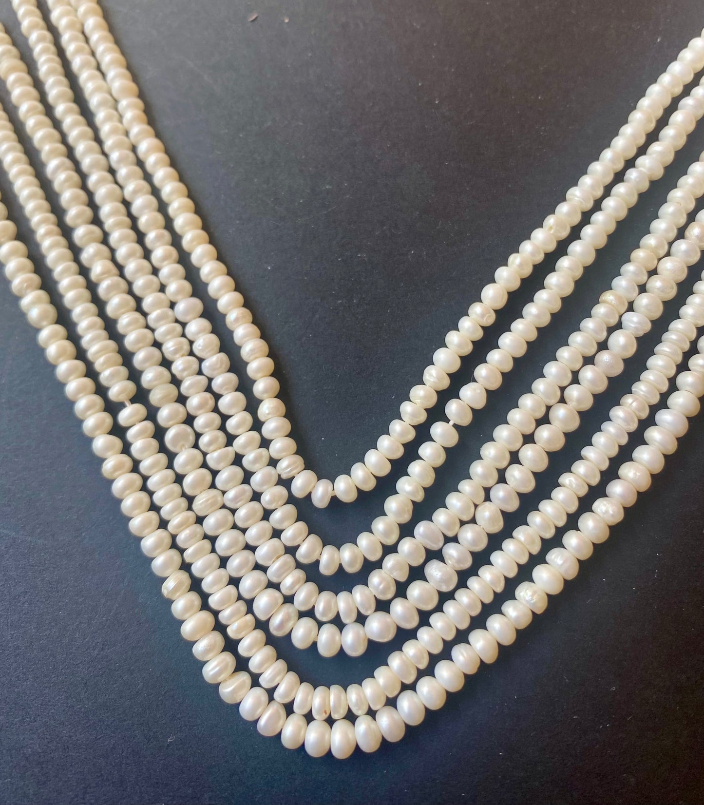 Multiple stunning strands of 3.5-4.0mm white freshwater pearls, showcasing their smooth texture against a contrasting black background.