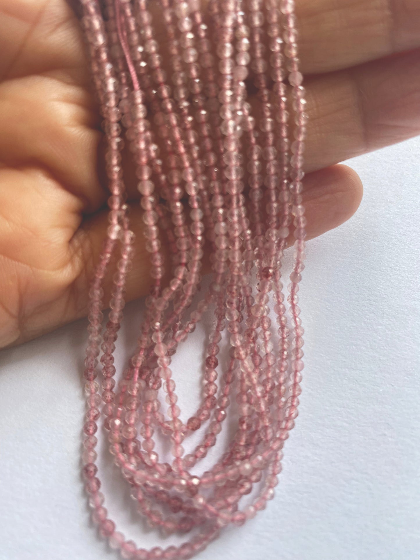 Strawberry Quartz faceted rondelles laid out in rows, revealing consistent bead quality and symmetry.