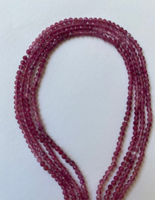 Micro-faceted beads, 2-2.2mm in size, artfully laid out on a white surface, highlighting their vibrant colour.