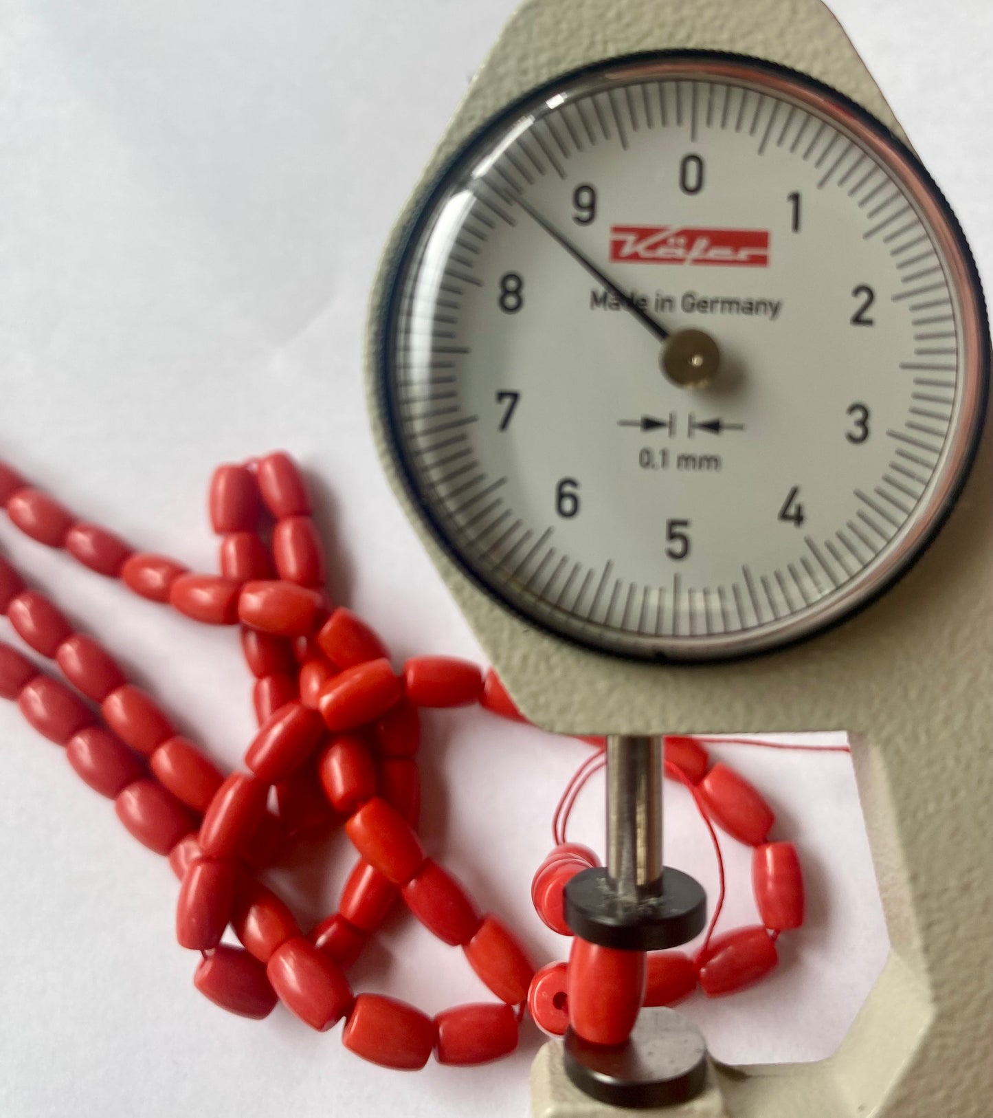 A dial gauge displaying a delicate Taiwan Coral Beads strand, highlighting size and measurement.