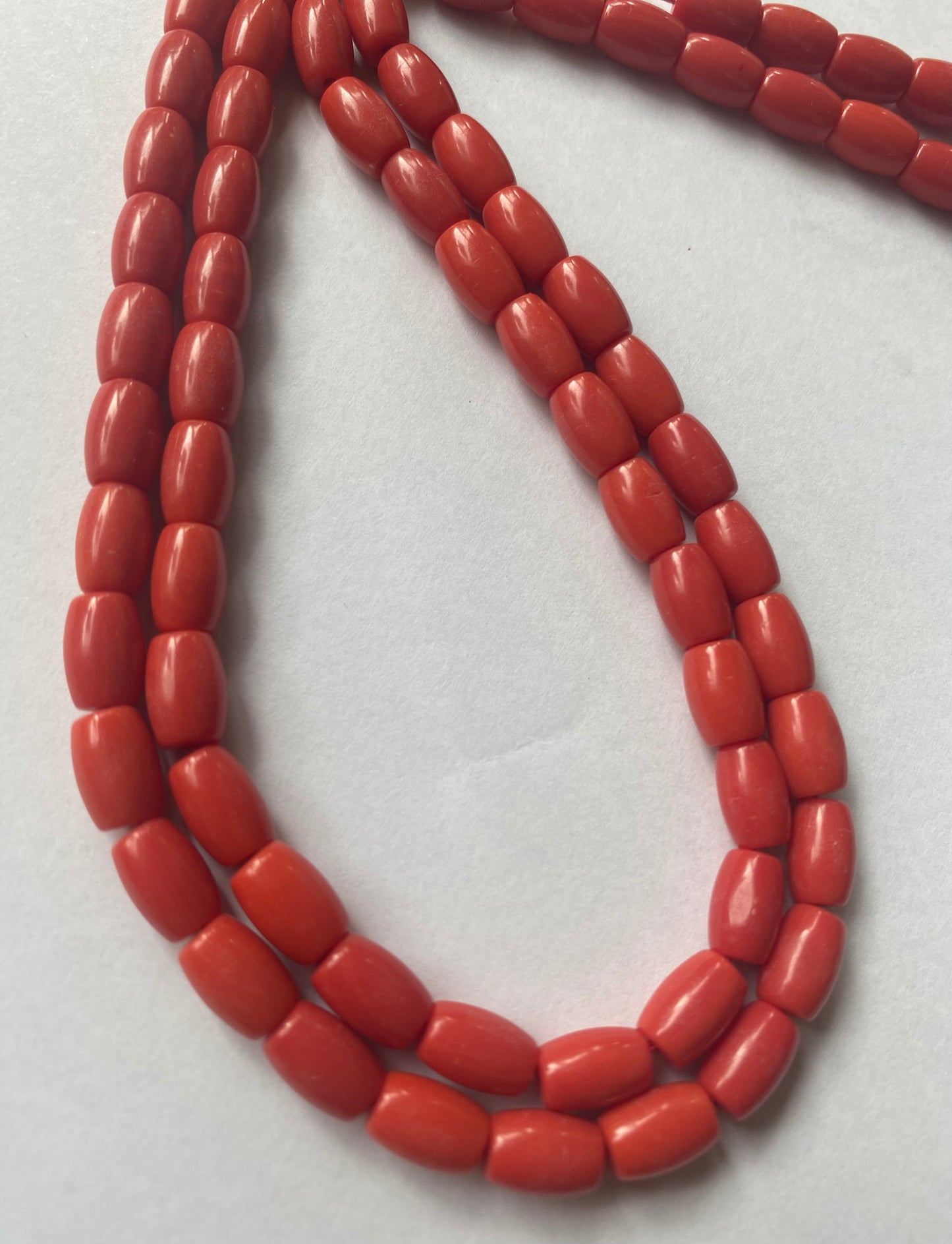 A delicate strand of Taiwan Coral stone beads elegantly displayed on a smooth white surface.