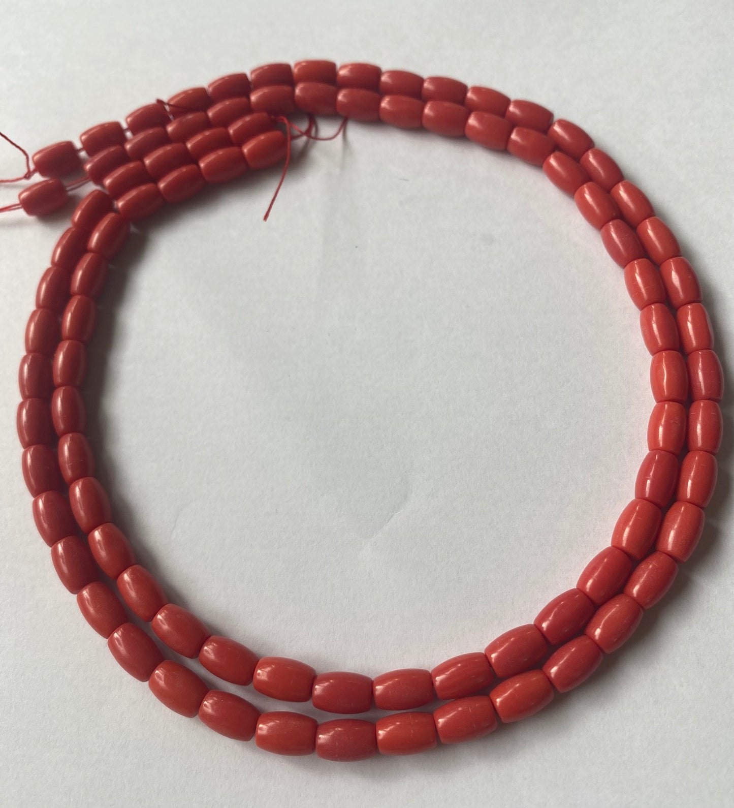 A strand of lustrous Taiwan coral beads laid out on a white surface, highlighting their elegance.