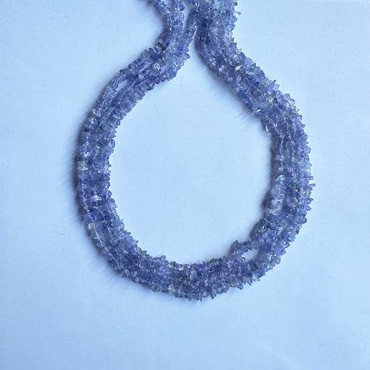 Tanzanite chips arranged in a strand, displaying their uneven surfaces and rich gemstone textures.