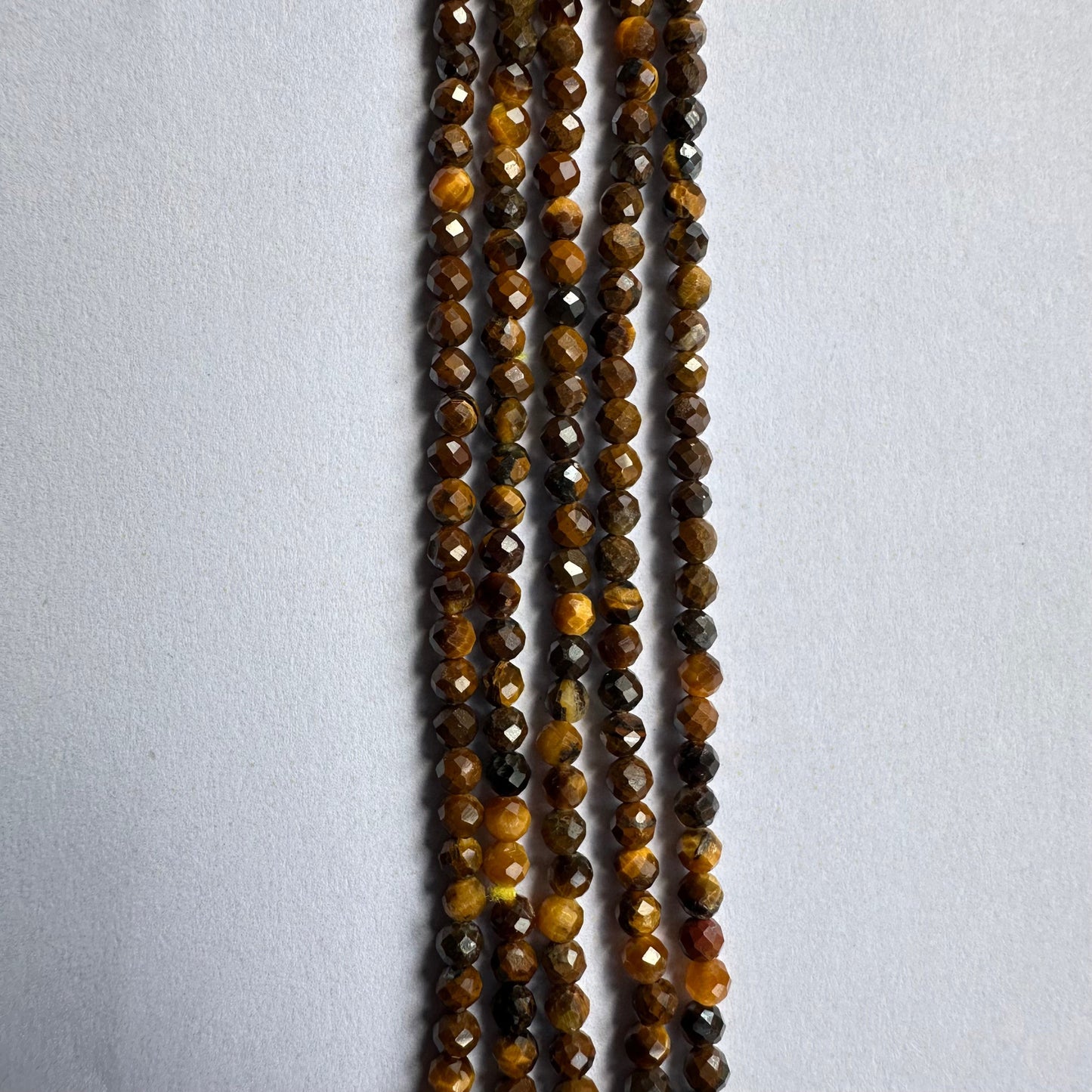 Jewellery artisan lines up Tiger Eye rondelles, highlighting the quality and colour variation.