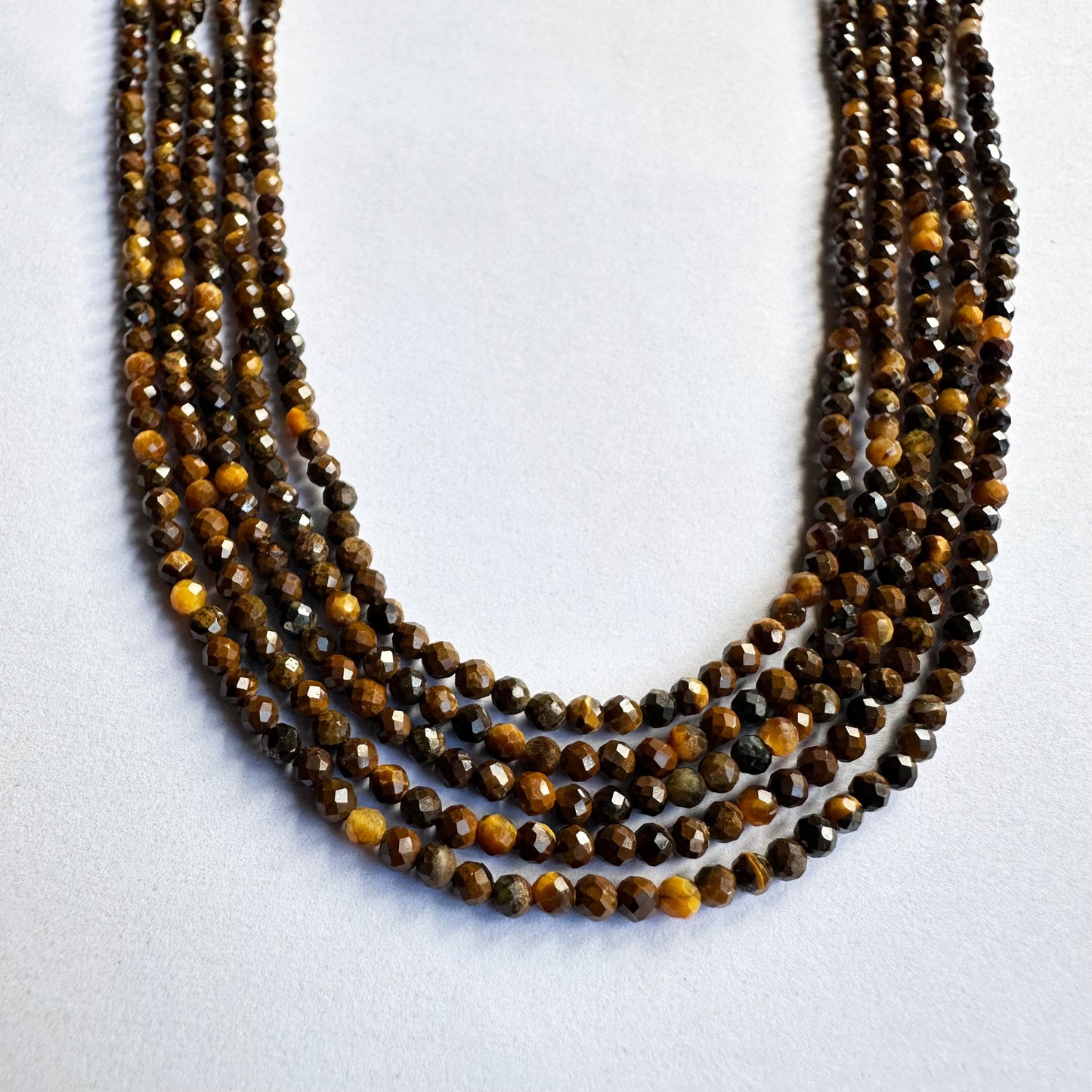 Tiger Eye gemstone beads sparkle under light, enhancing their detailed micro-faceted surface.