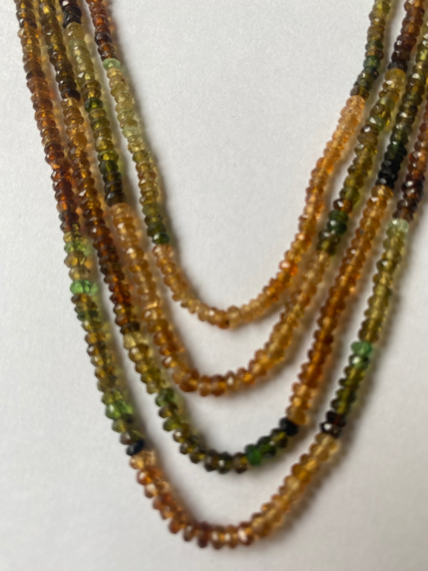Close-up of a person’s hand showcasing a colourful assortment of 3-3.5mm tourmaline beads.