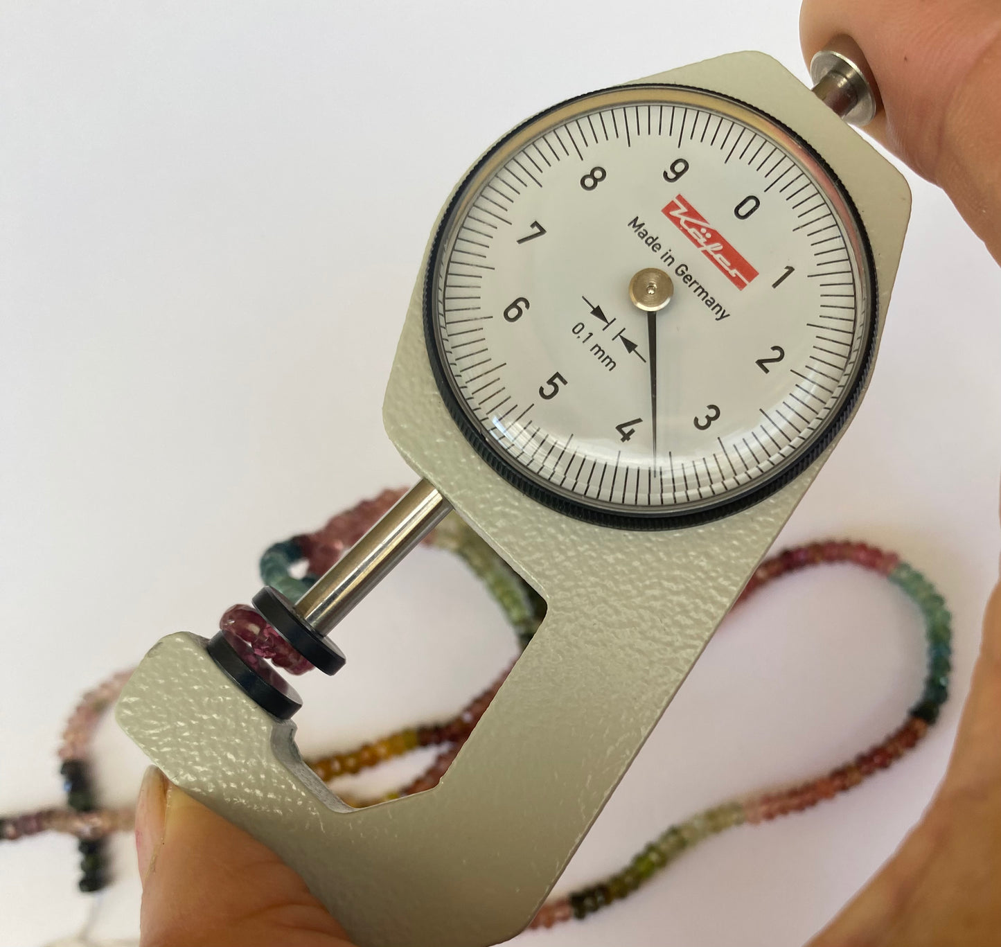 A person measuring with a gauge showcasing a semi-precious tourmaline of 3.5-3.9mm.