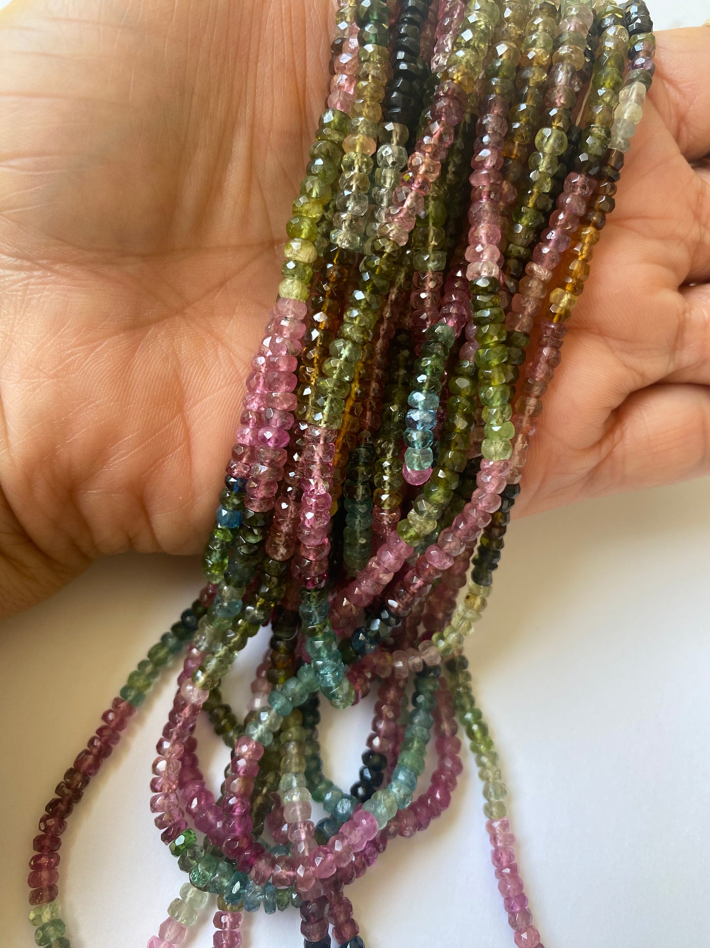 A collection of 3.5-4mm tourmaline beads in various colours, arranged in a row, highlighting their natural beauty.