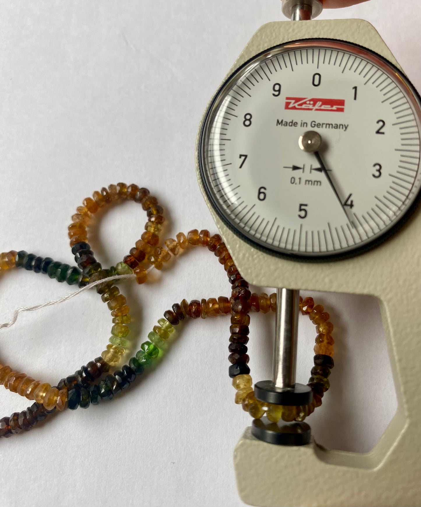 A dial gauge displaying a delicate 4mm tourmaline faceted rondelle strand, highlighting size and measurement