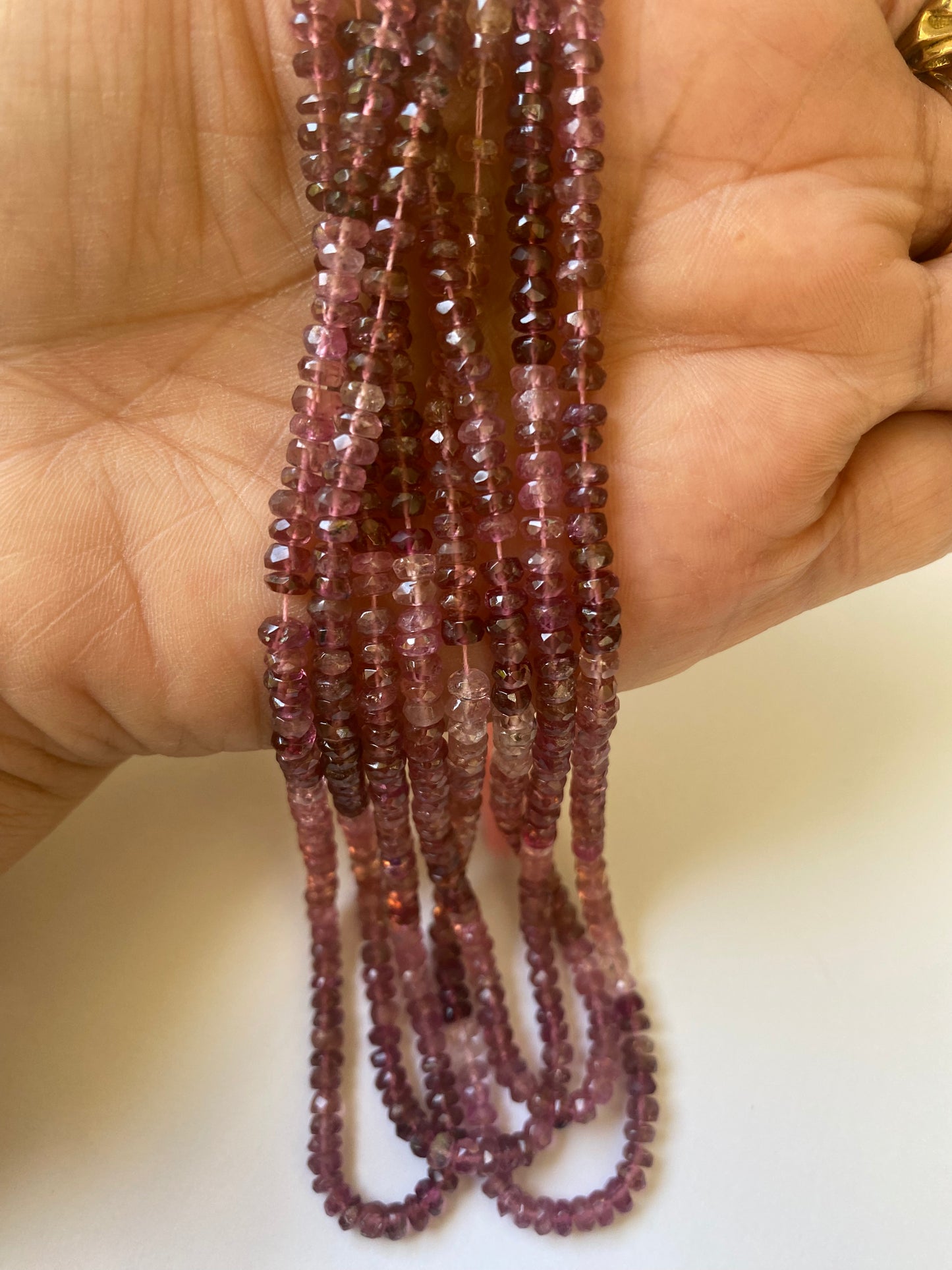 Close-up image of a necklace adorned with 3.8-4.0mm red and pink faceted rondelle tourmaline beads.