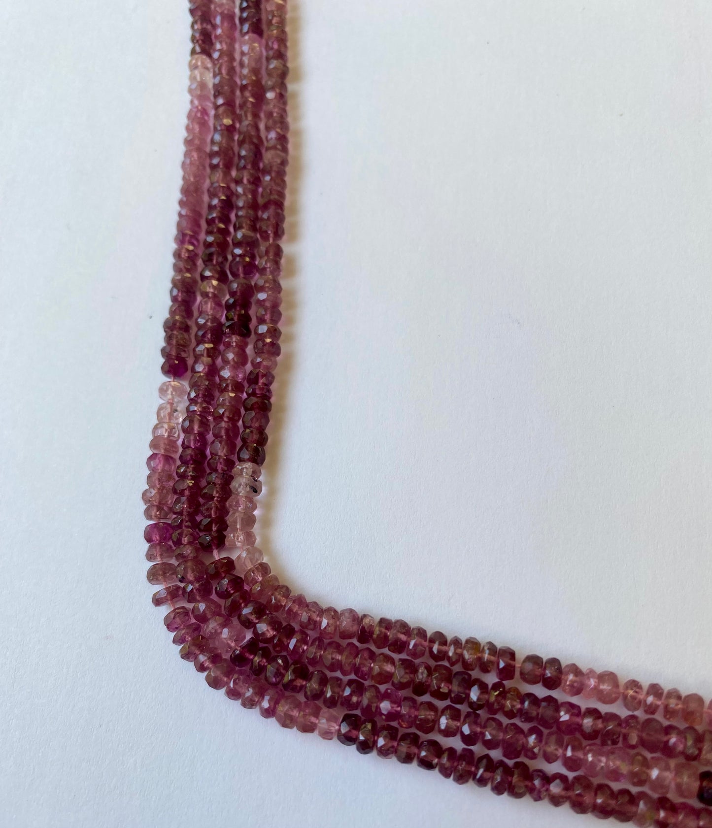 Close-up of a strands featuring faceted rondelle tourmaline beads in red and pink, measuring 3.8-4.0mm