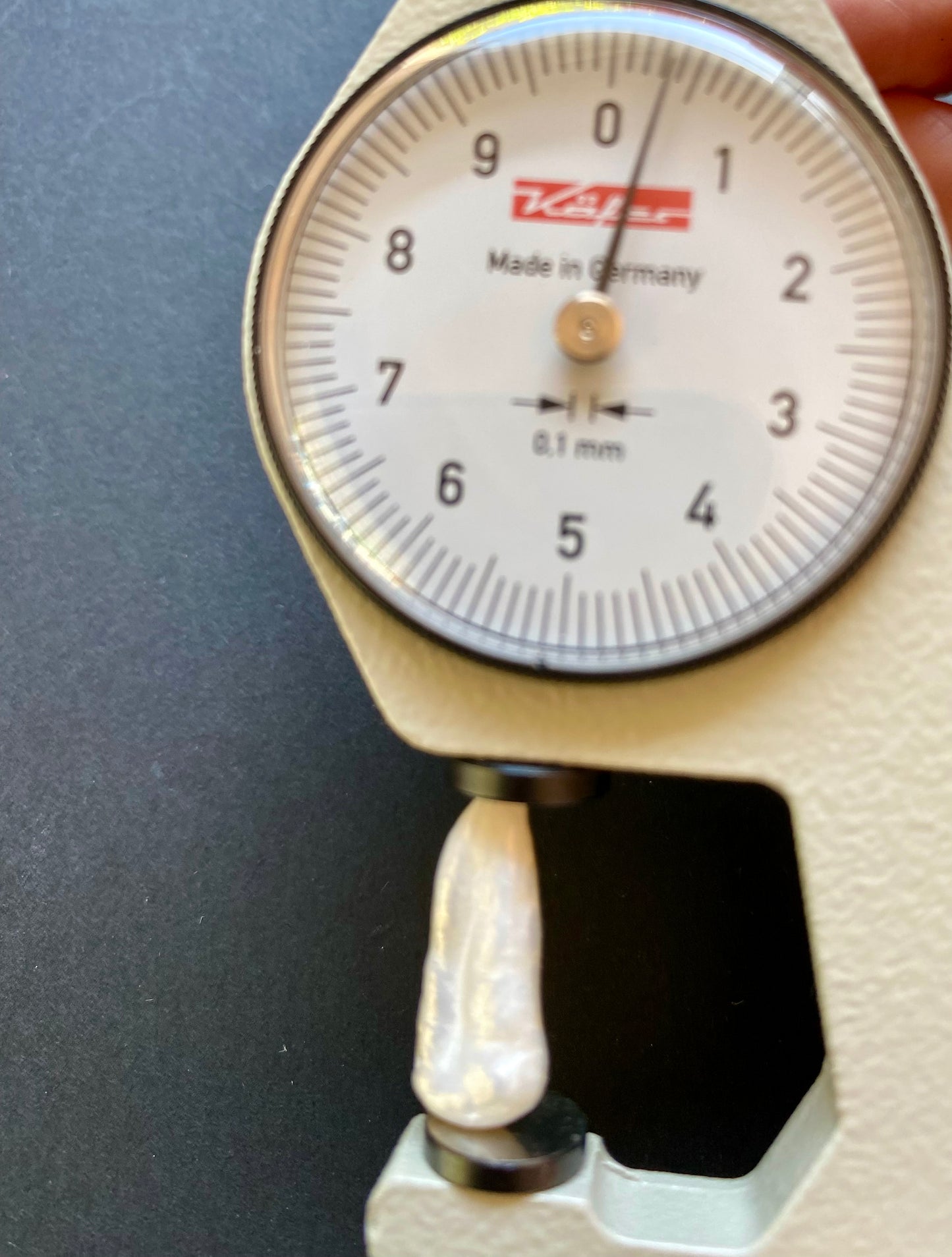 Close-up of a person holding a small white Baroque pearl on a scale, emphasising its undrilled nature and elegance.