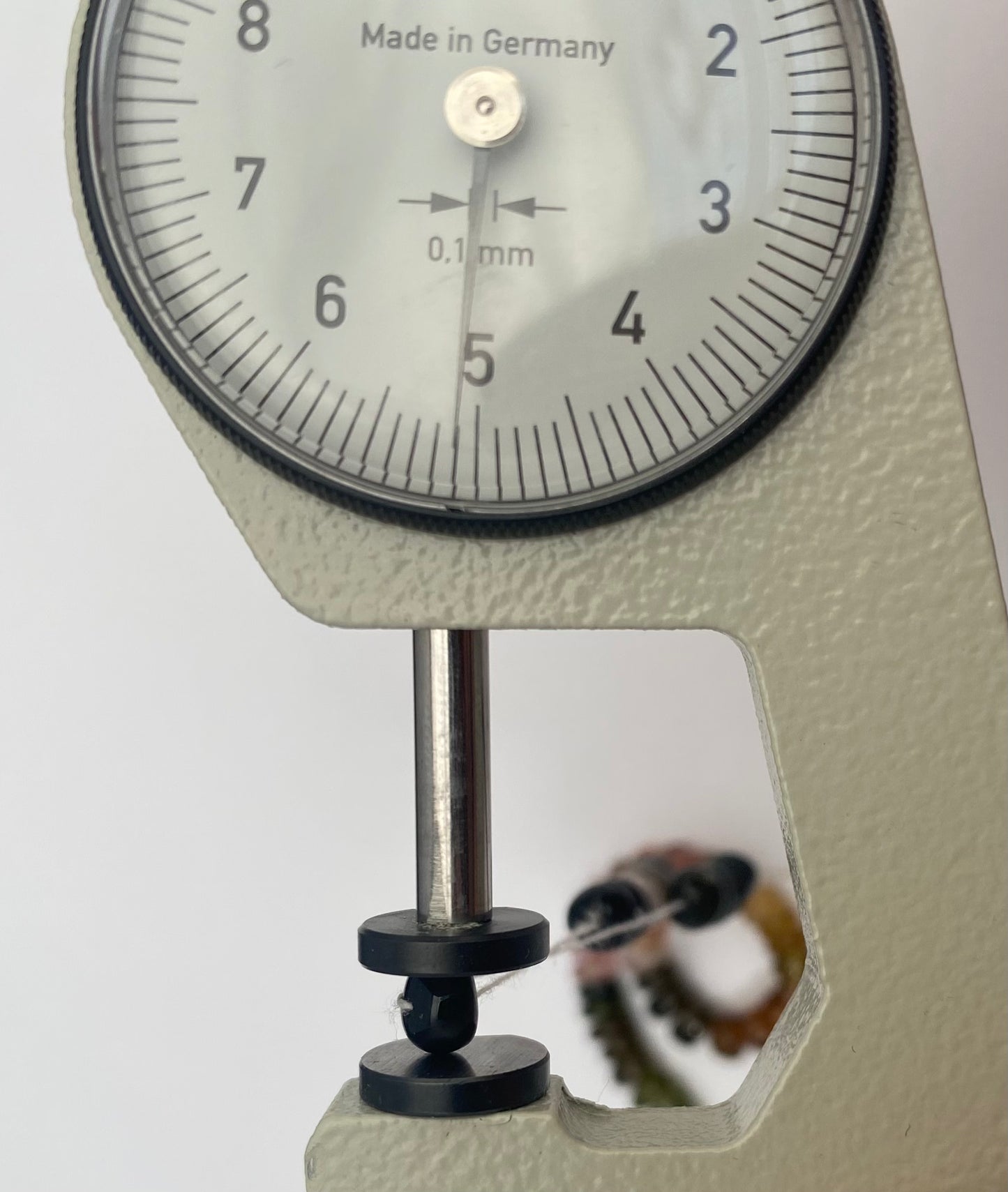 Close-up of a dial gauge measuring a colourful watermelon tourmaline bracelet featuring smooth rondelle beads.