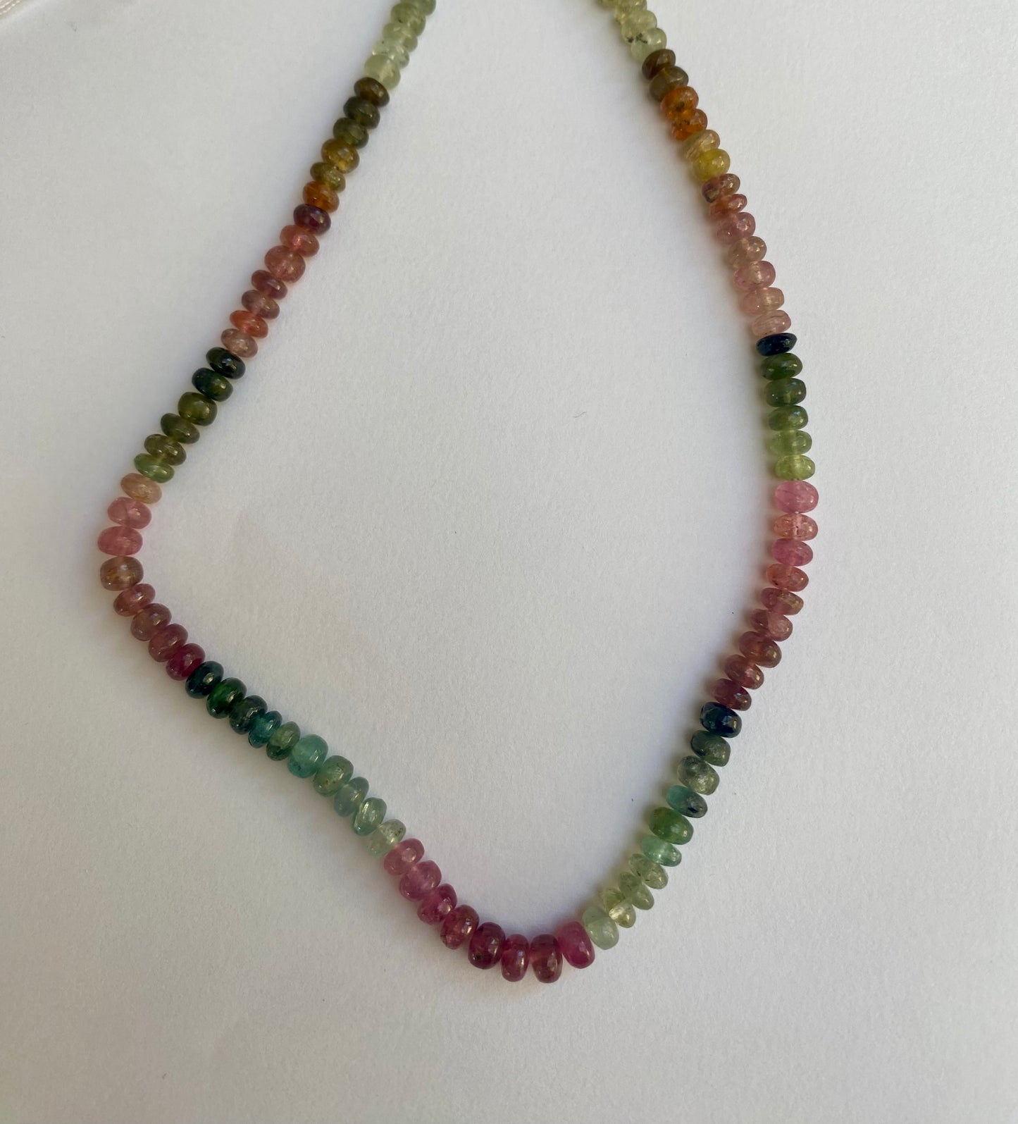 Vibrant watermelon tourmaline smooth rondelle beads in pink and green colours on a white surface.