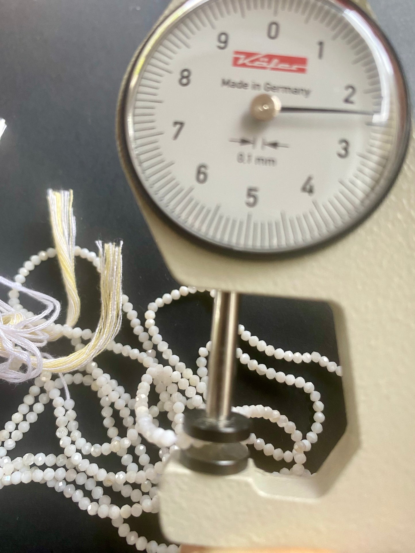 Close-up of a measuring dial gauge tool alongside a string, highlighting the precision of measurements for Opal jewellery.