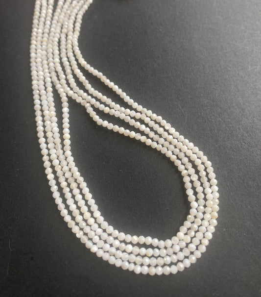 A person holding a smooth strand of Opal beads, measuring 2.25-2.5mm, showcasing their elegant white colour.