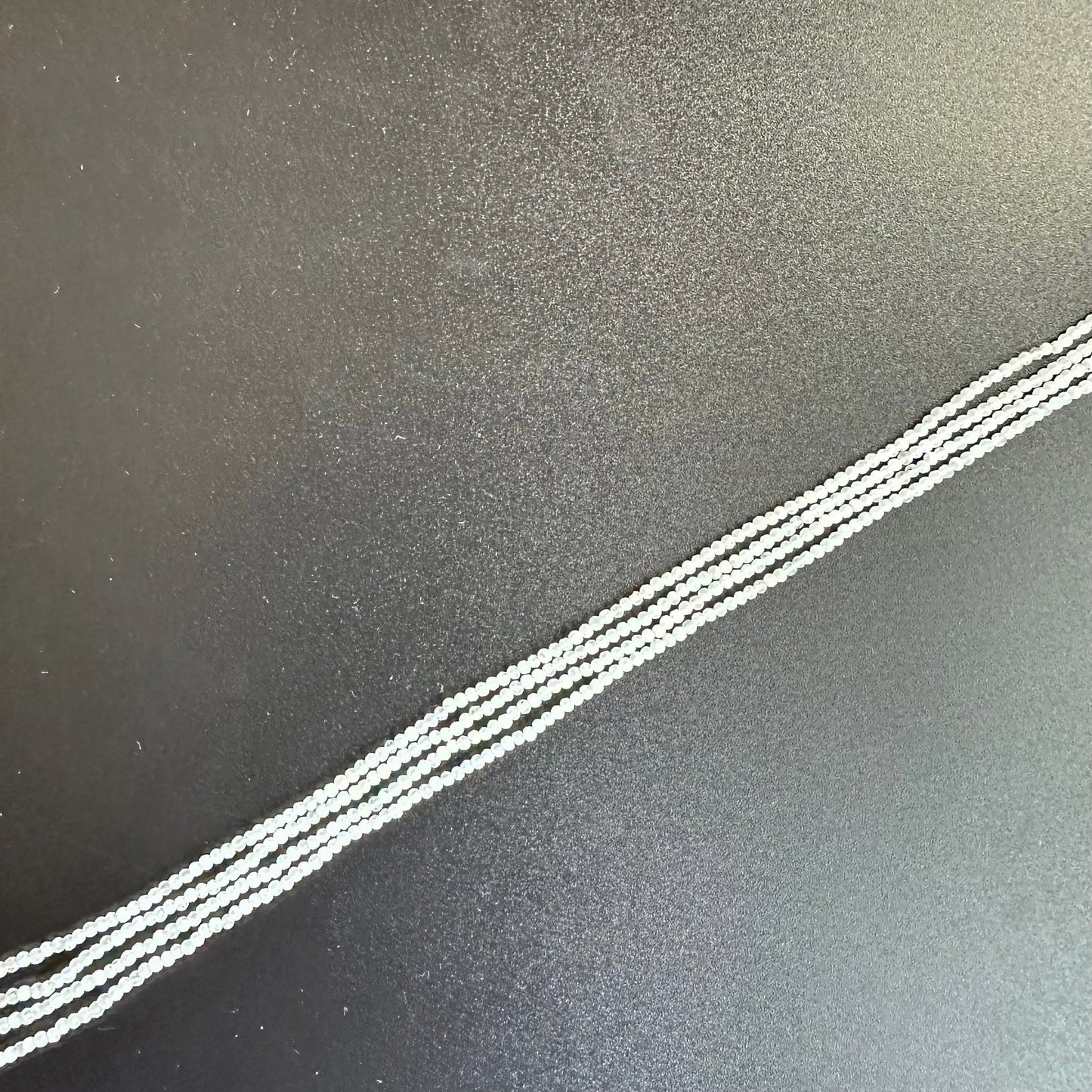 Close-up of White Rainbow Moonstone beads reveals their subtle iridescence and fine faceting.