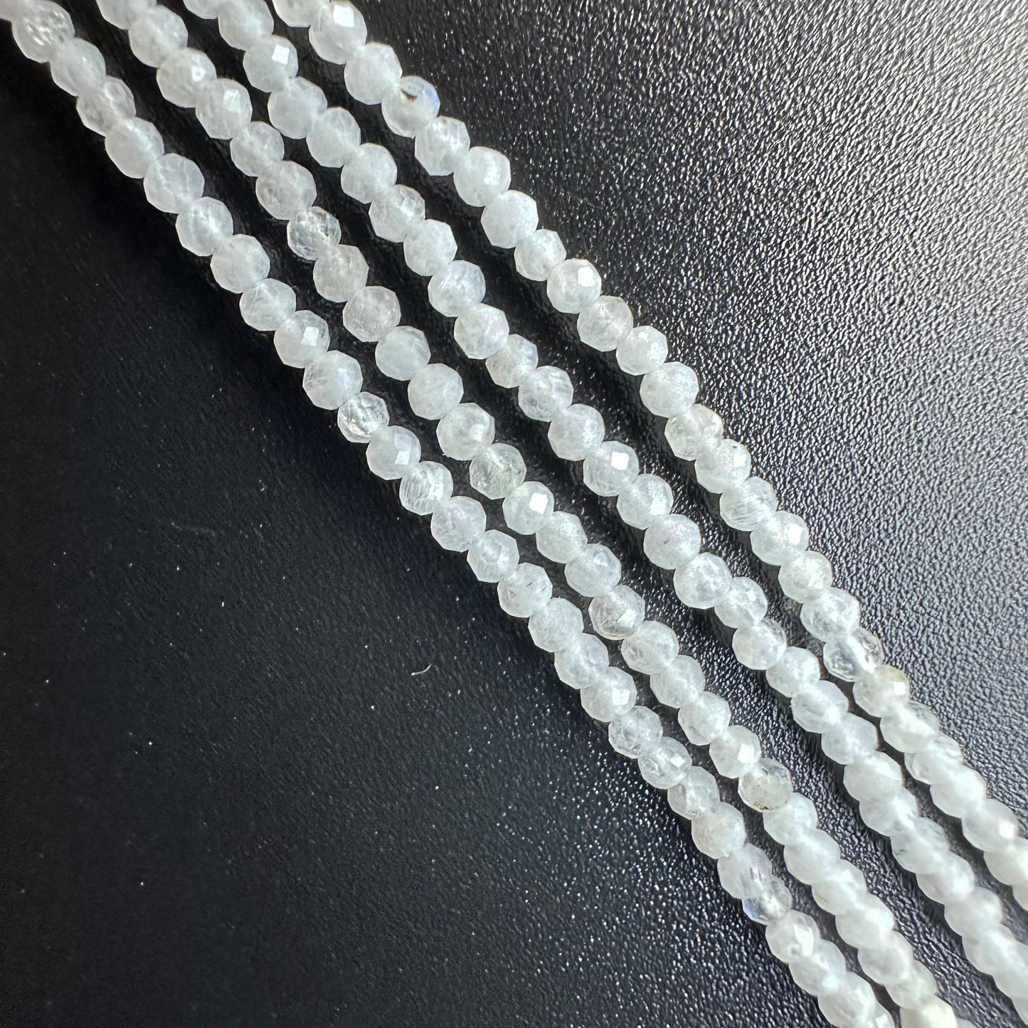 A jewellery designer arranges White Rainbow Moonstone beads, creating a refined gemstone piece.