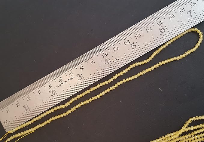 A person uses a ruler to measure a yellow Chalcedony stone, sized around 2.5mm.