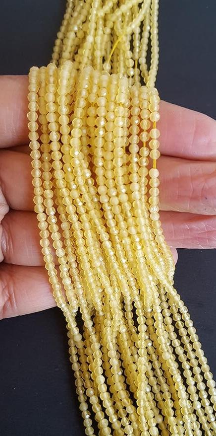 Close-up of a person holding a stunning yellow Chalcedony gemstone strand, highlighting its intricate facets.