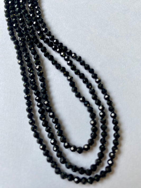 Stylish strands made of 3.0mm black spinel micro-faceted rondelle beads, highlighting its sophisticated look on a smooth white background