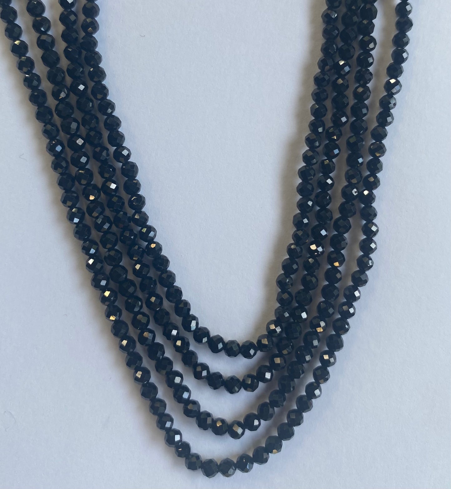 A close-up of a multiple strands featuring black spinel micro-faceted rondelle beads, measuring 3.0mm in size.