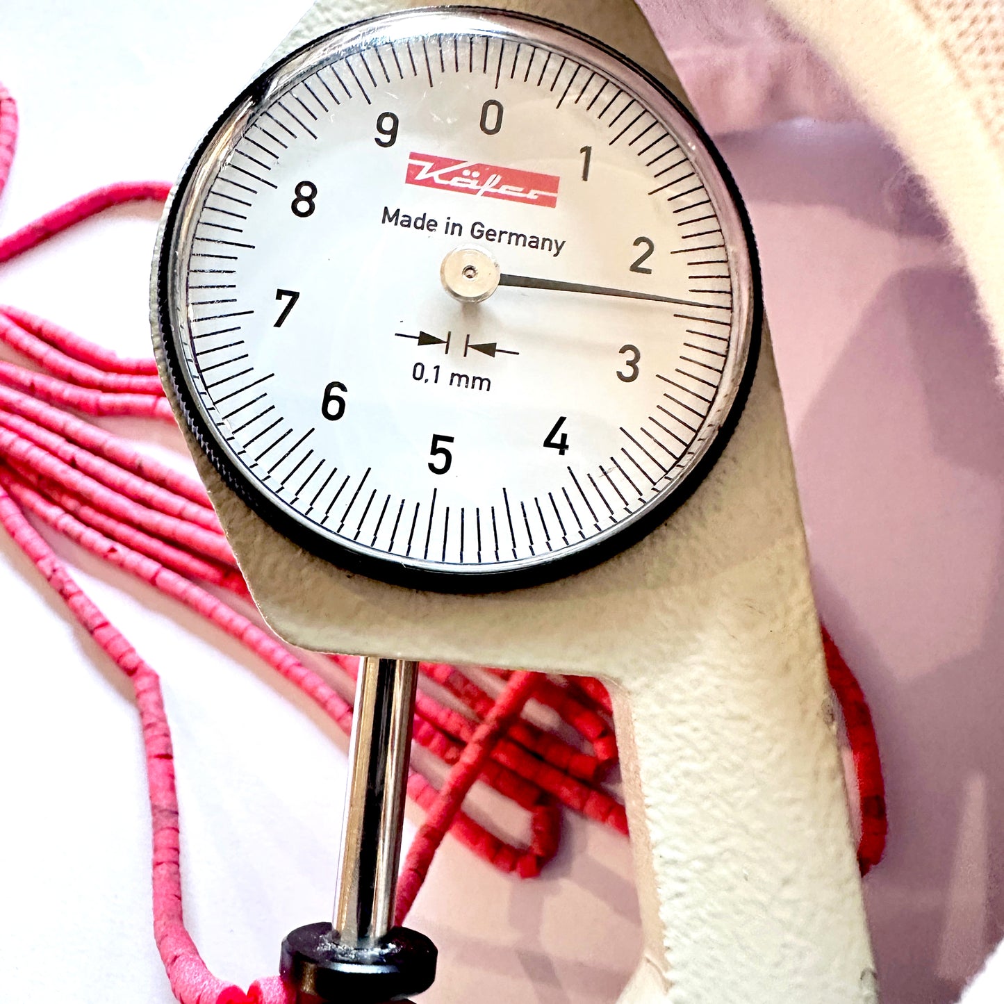A dial gauge measures the Afghan Tube Shaped Heishi 2.3- 2.4mm gemstone.
