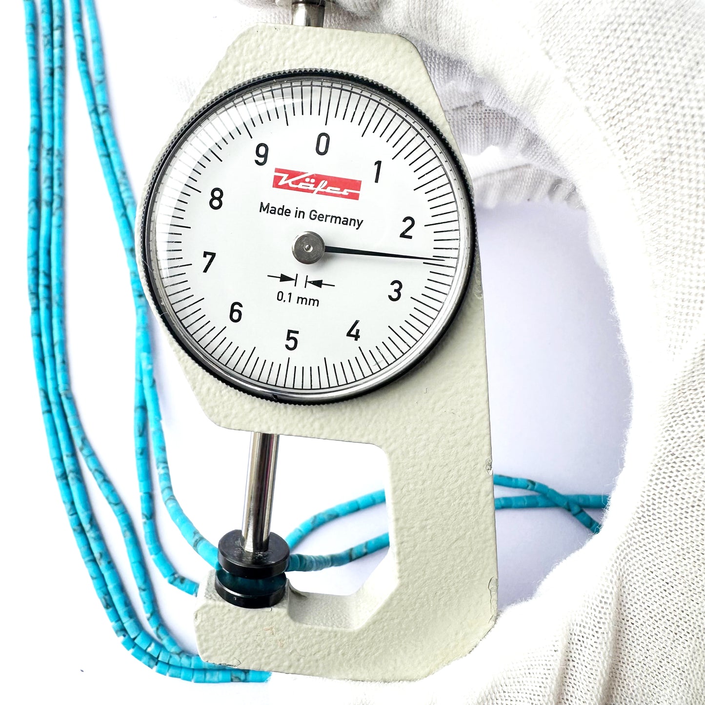 A dial gauge measures the Afghan Tube Heishi 2.3-2.5mm gemstone
