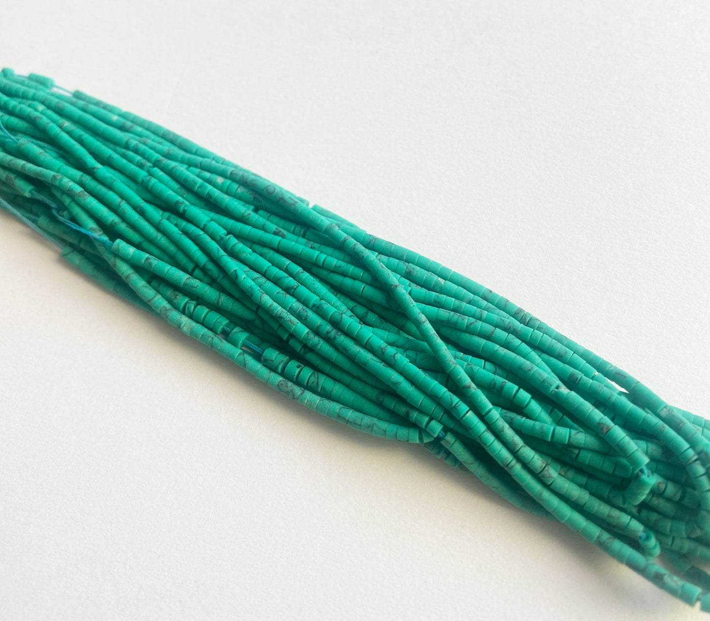 Close-up of Afghan Heishi gemstone beads showing soft earthen tones and consistent cylindrical cuts.