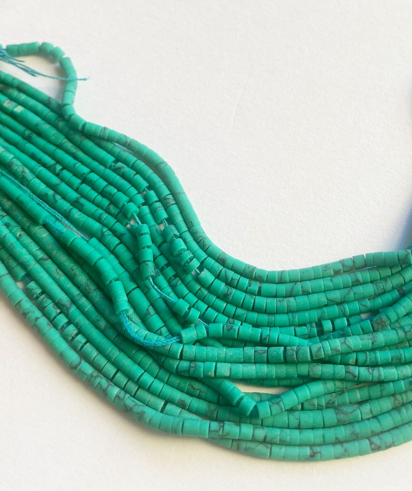 Strand of Afghan 2mm Heishi beads displayed in aligned rows with subtle shimmer and artisanal quality.