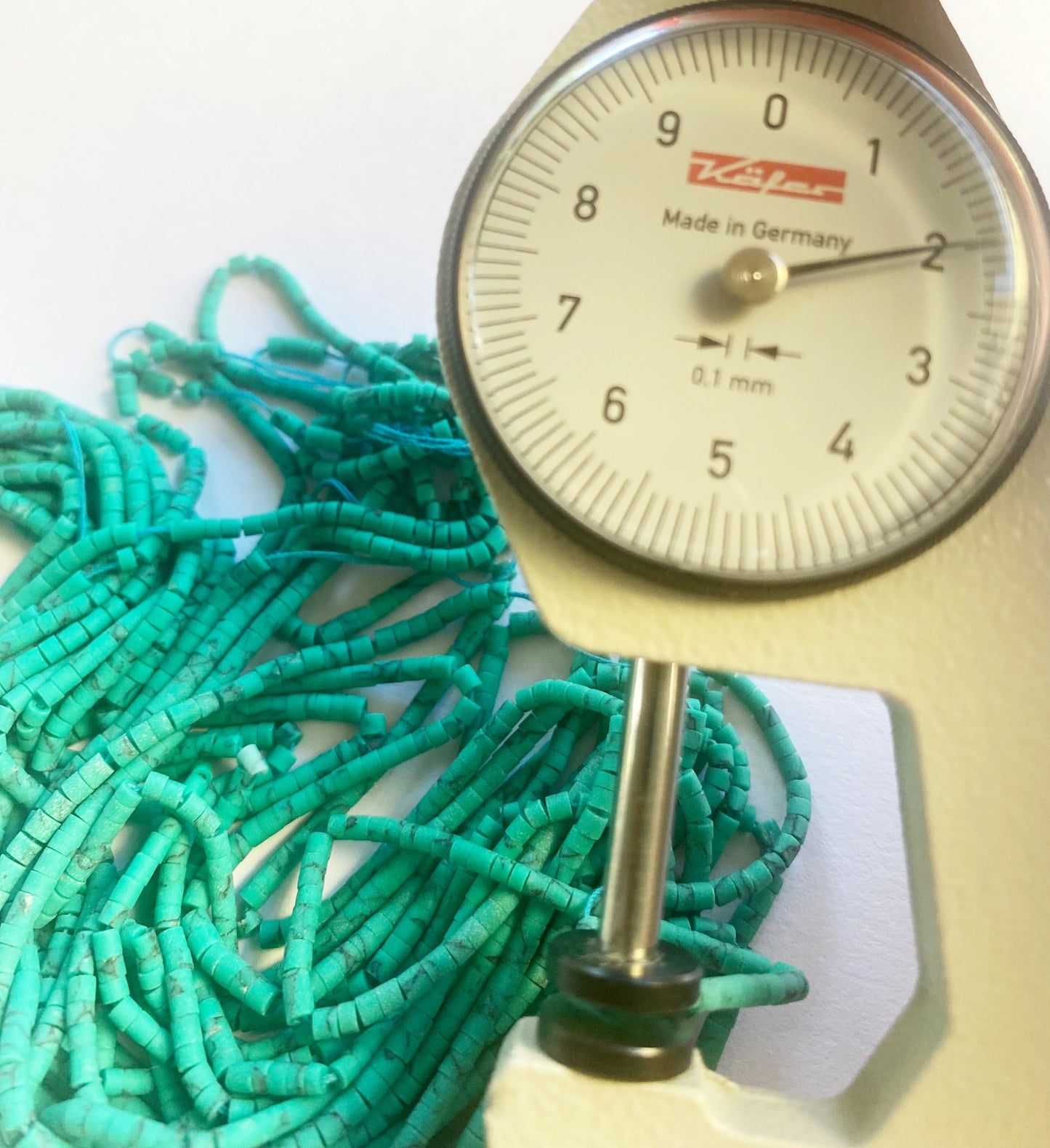 A dial gauge measures the Afghan Tube Shaped Heishi 2mm gemstone.