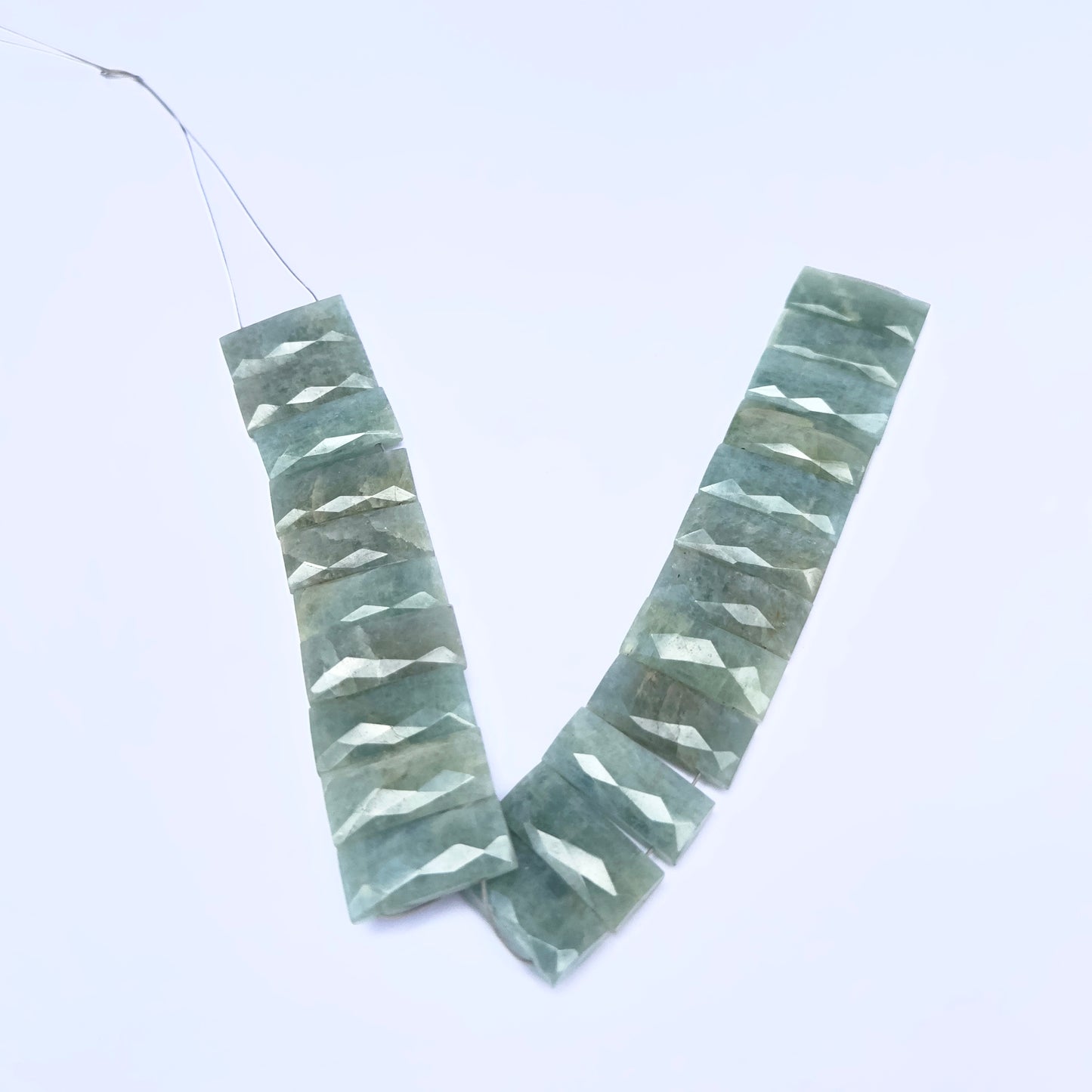 Amazonite gemstone beads laid flat to highlight their faceted surface and rectangular shape.