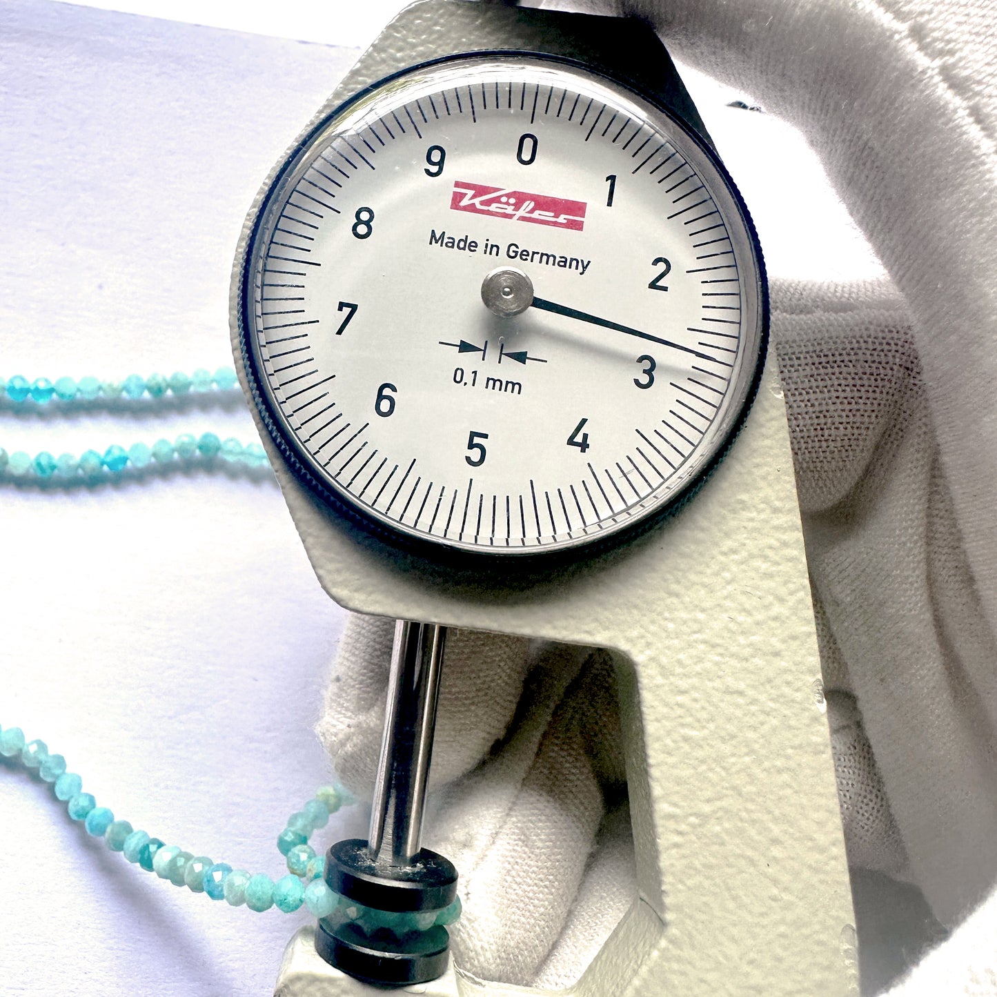 A dial gauge measures the Amazonite faceted rondelle 2.7mm gemstone.