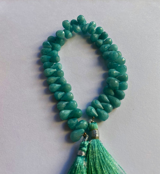 . Close-up of amazonite gemstone beads showing their faceted teardrop cut and natural shimmer