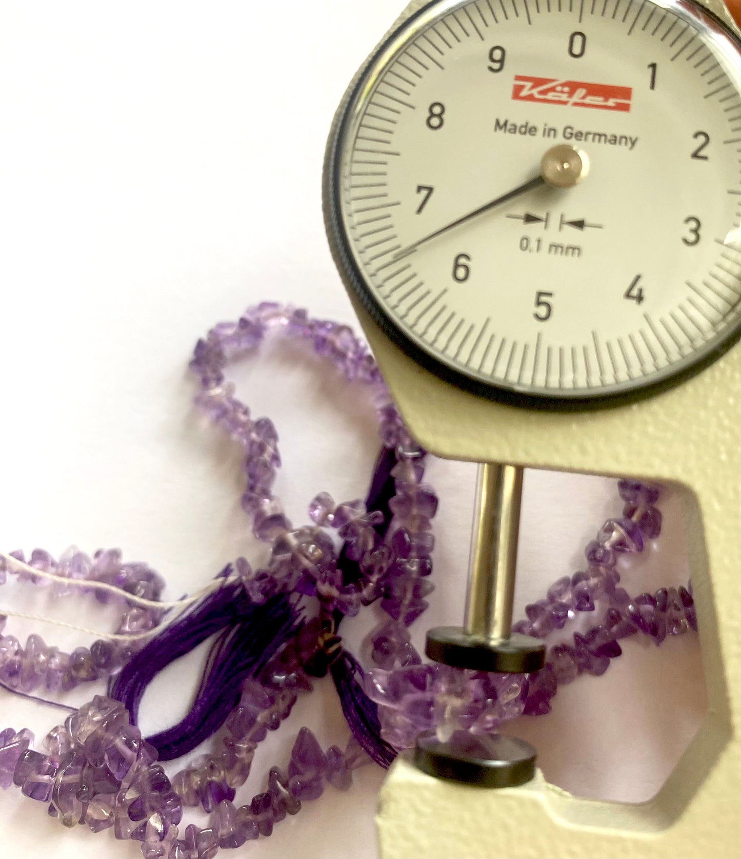 A dial gauge measures the Amethyst chip 5-7mm gemstone.