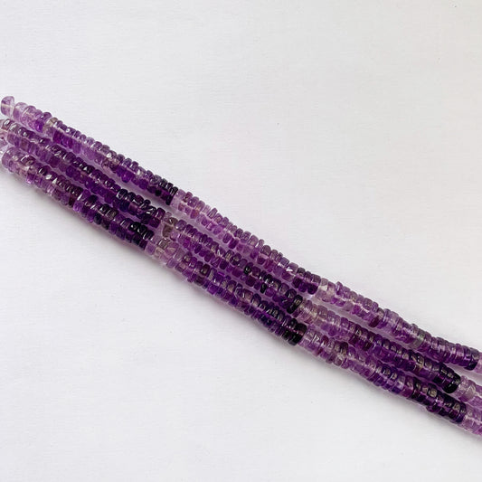 Close-up of polished Amethyst gemstones cut in smooth Heishi shape, arranged on a 20cm strand.