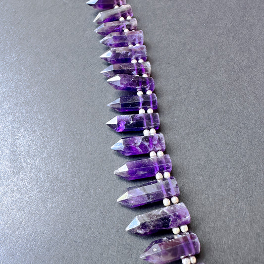 Close-up of amethyst stone beads with glossy finish and consistent sizing across 26 pieces.