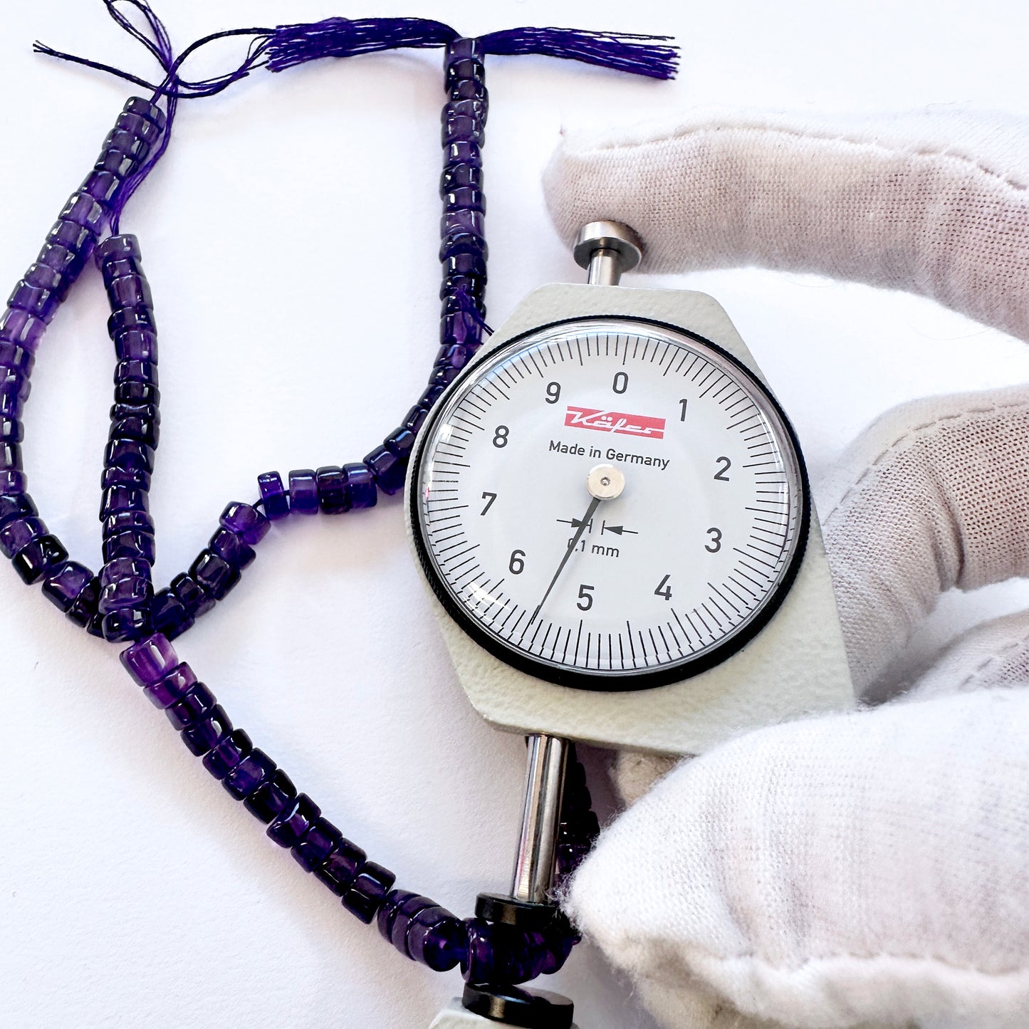 A dial gauge measures the Amethyst smooth wheel 5.5mm gemstone.
