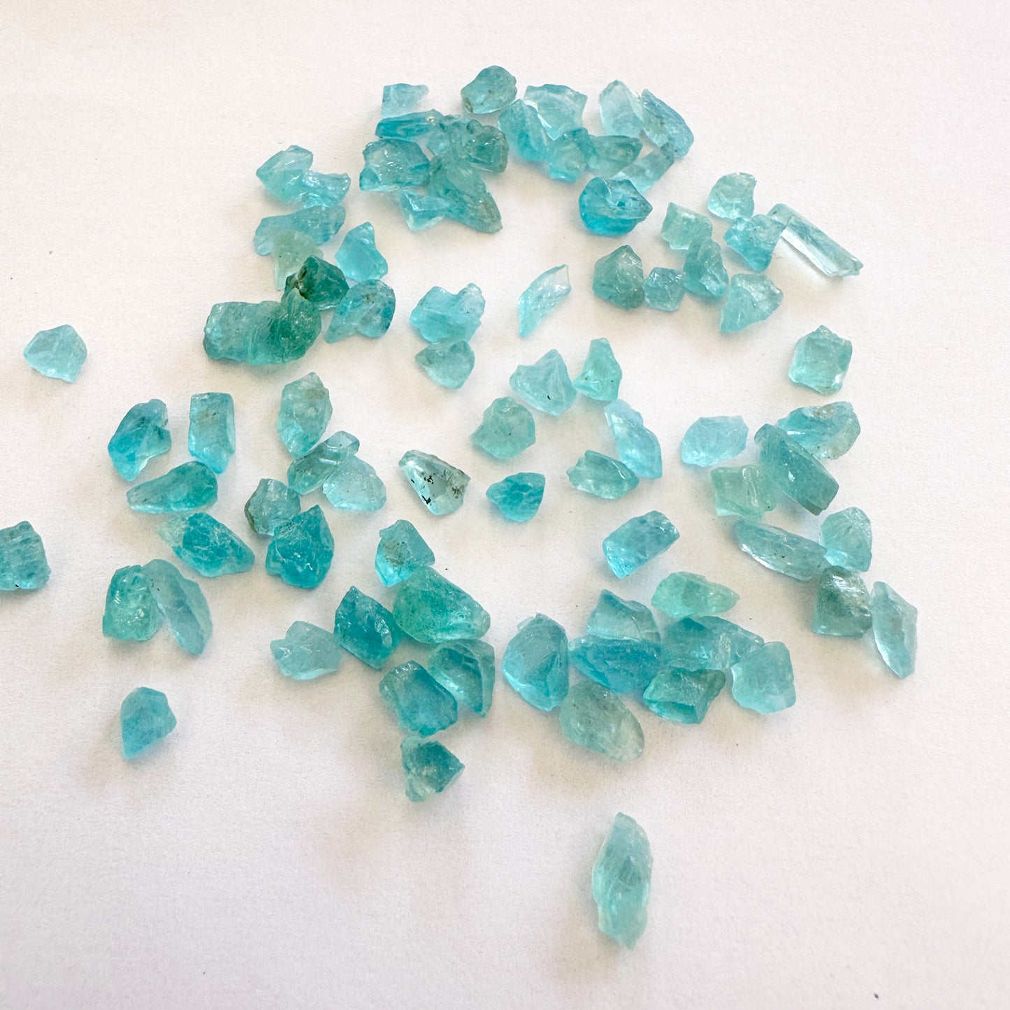 Apatite rough cut beads in blue-green tones arranged in a loose cluster.