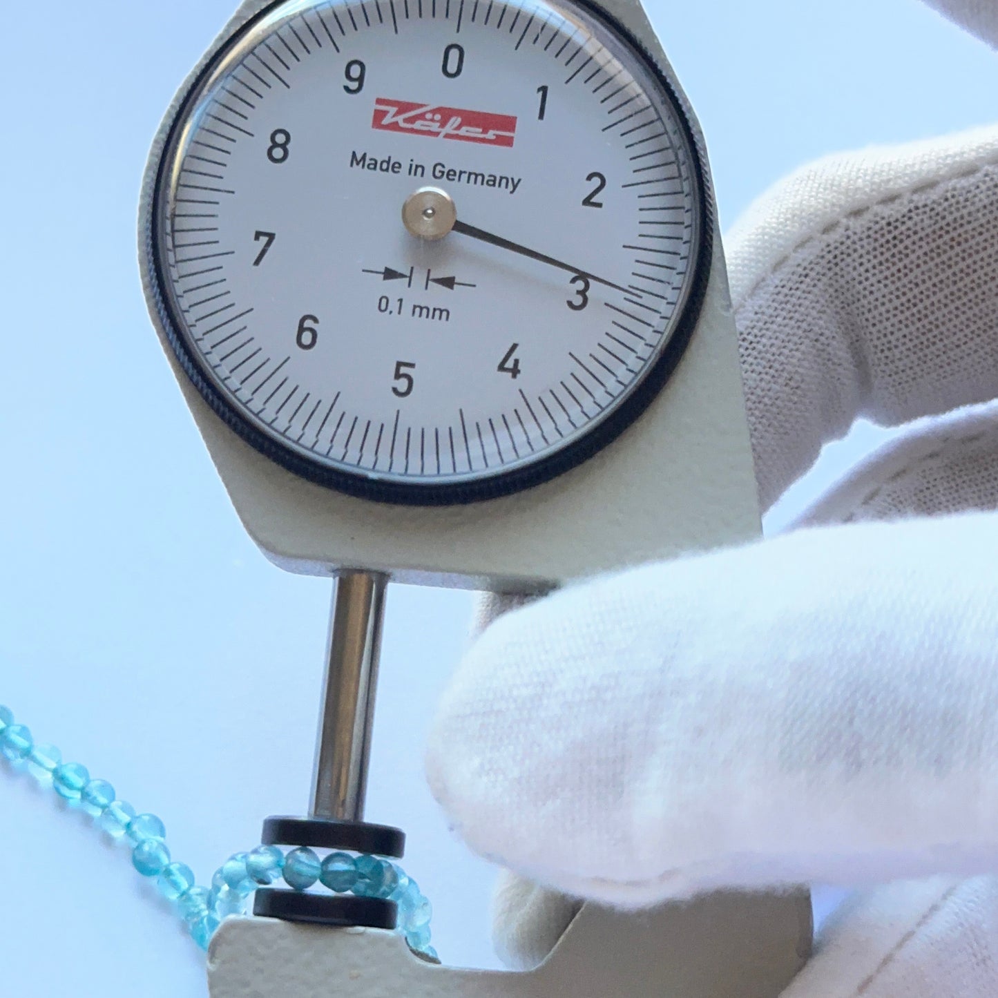 A dial gauge measures the Apatite smooth round 2.9mm gemstone.