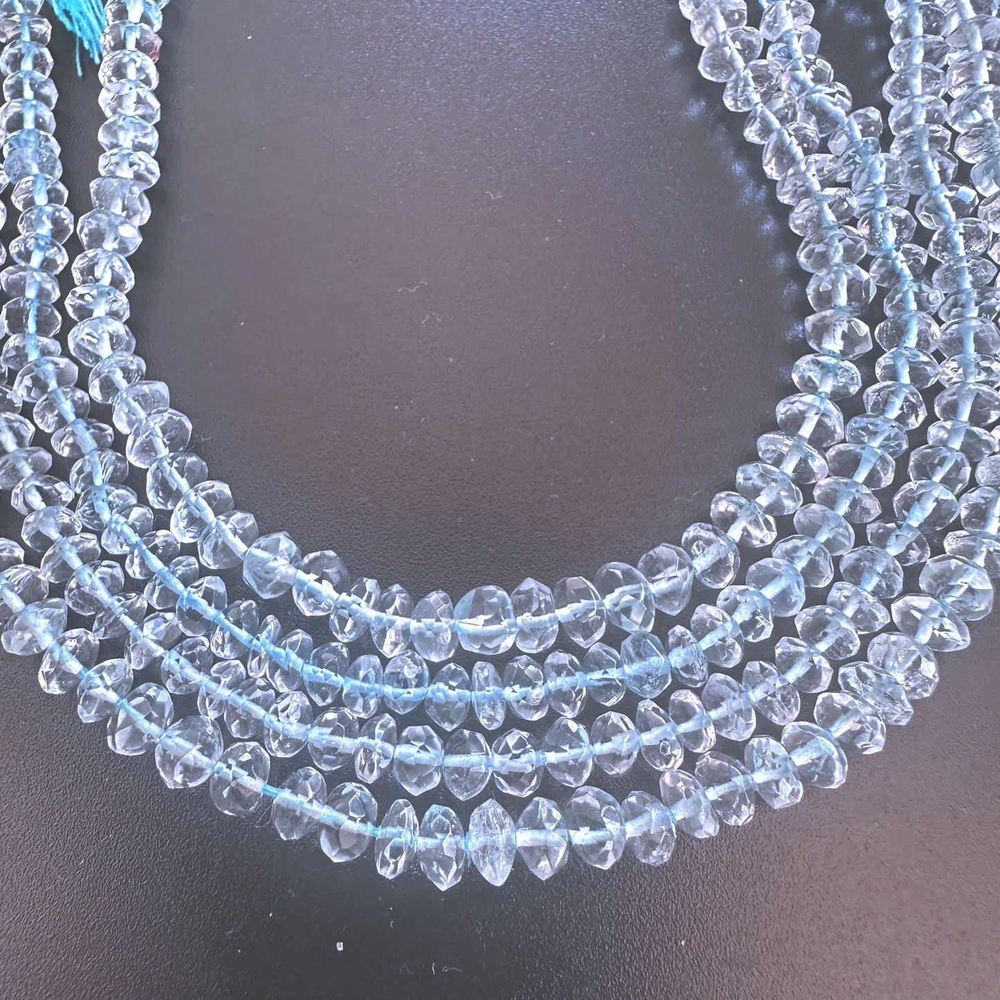 Strand of aquamarine beads with 4.5mm and 5mm sizes, reflecting light with subtle brilliance.