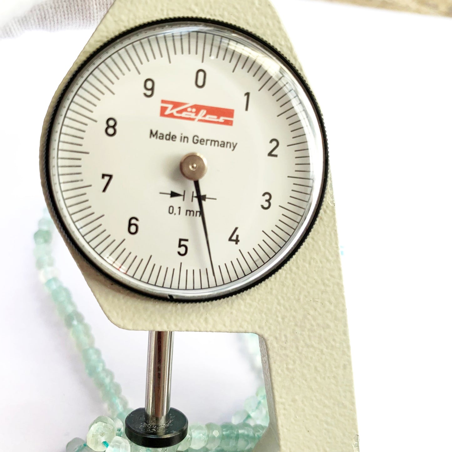 A dial gauge measures the Aquamarine faceted rondelle 4.5-5mm gemstone.